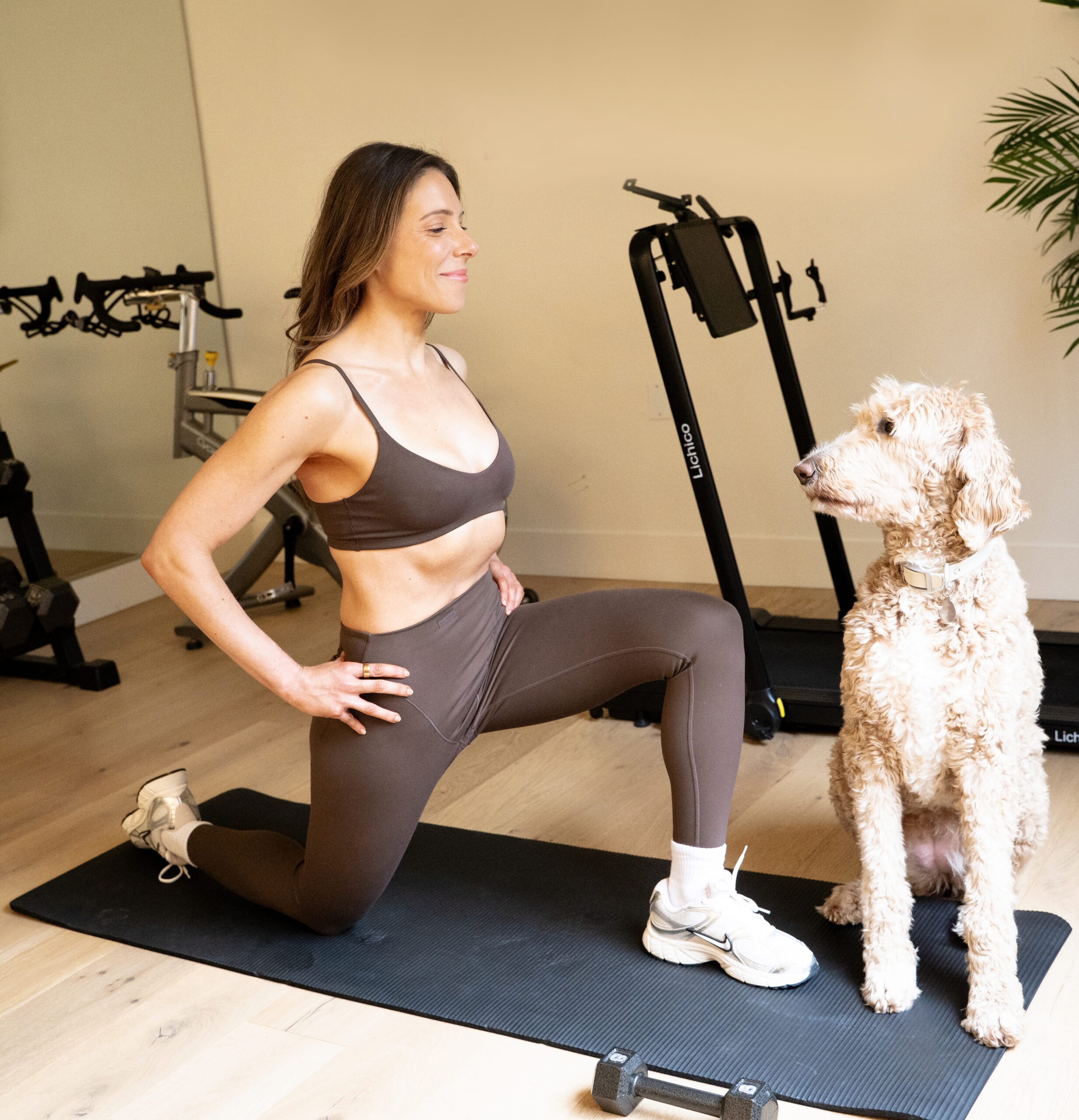 Woman doing a kneeling quad stretch at home with her dog in Portland personal training session