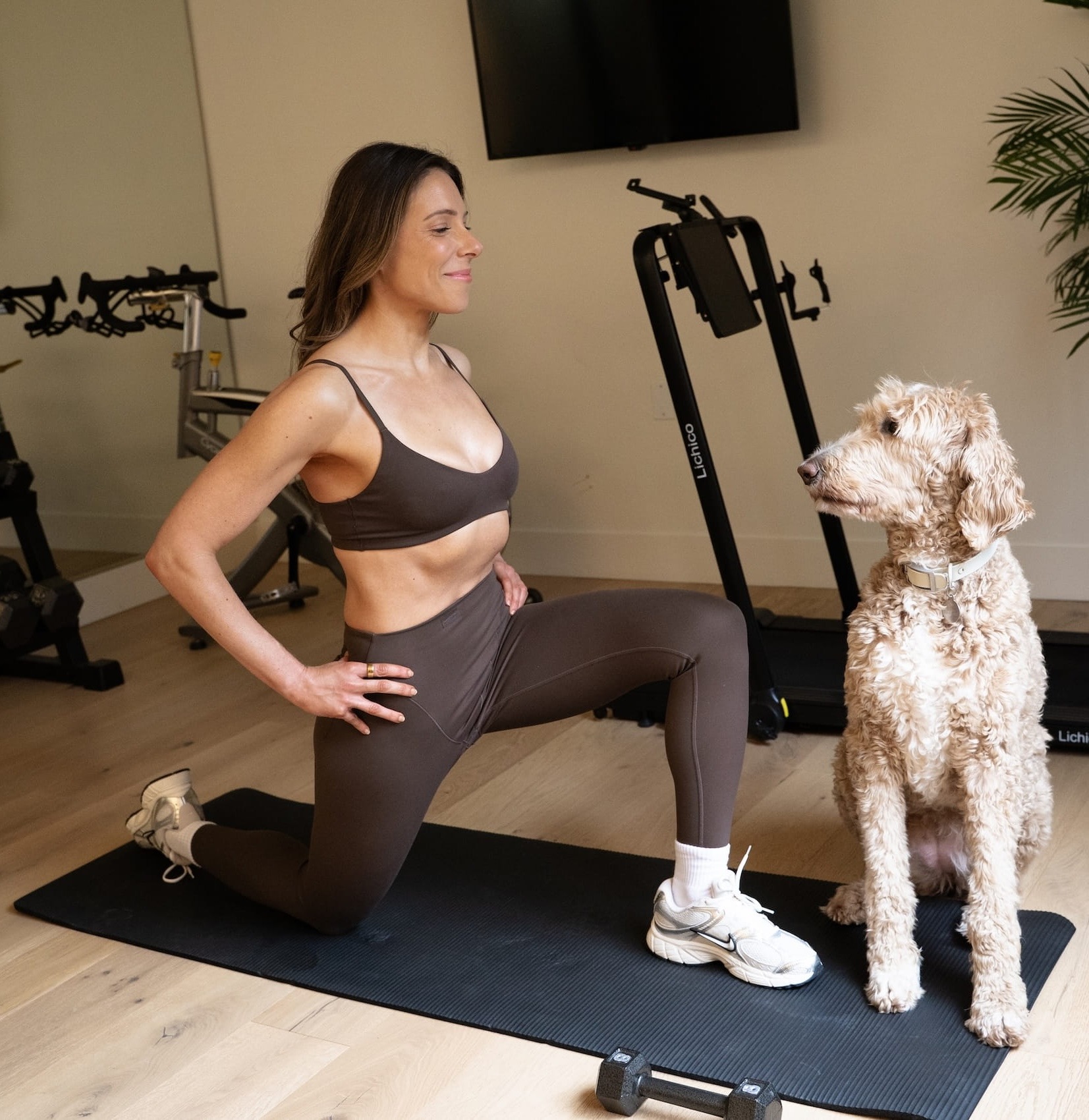 Woman doing a kneeling quad stretch at home with her dog in Portland personal training session