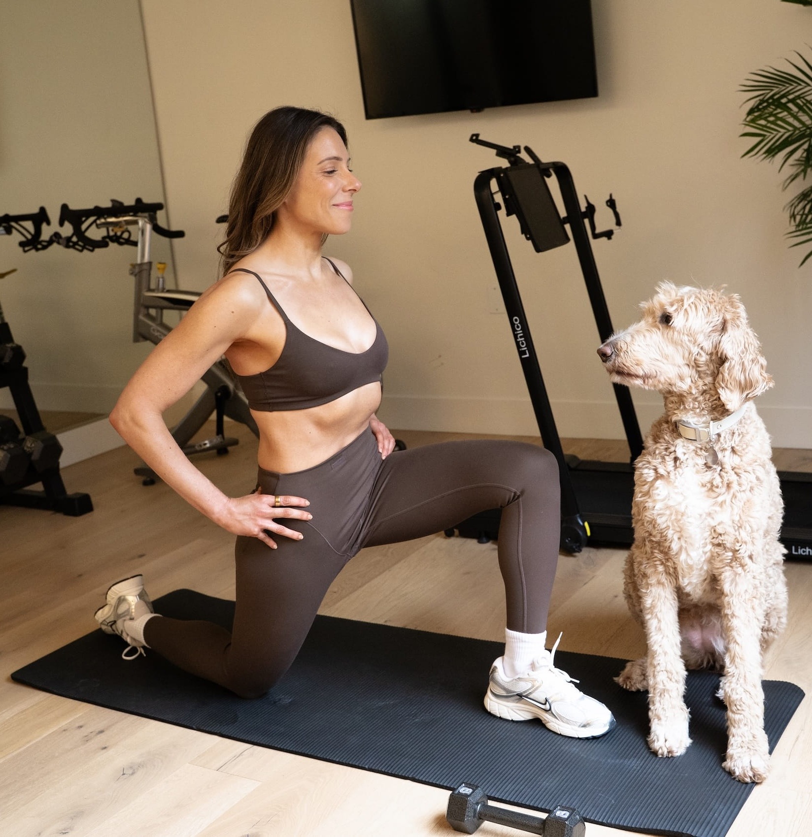 Woman doing a kneeling quad stretch at home with her dog in Portland personal training session