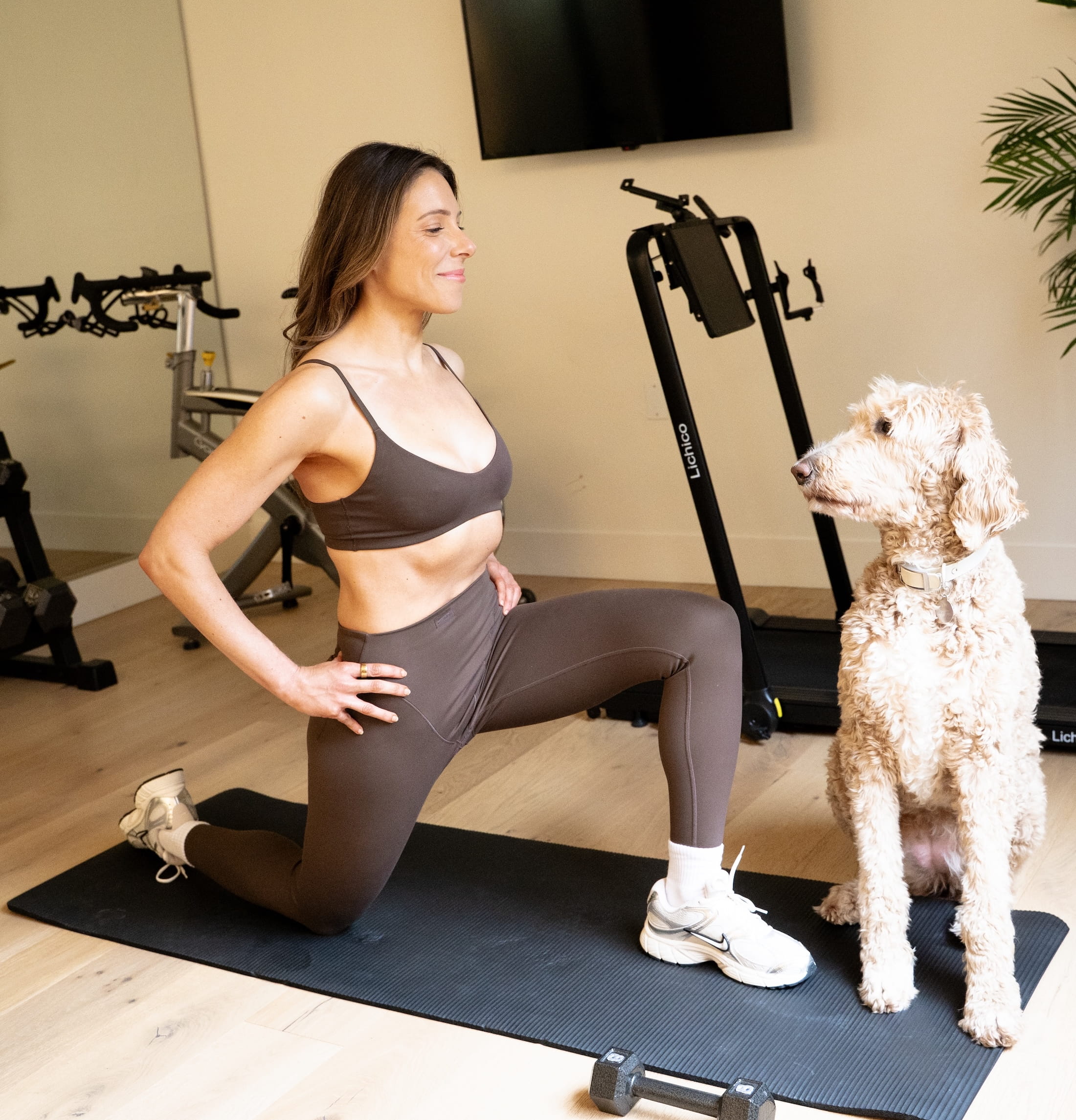 Woman doing a kneeling quad stretch at home with her dog in Portland personal training session