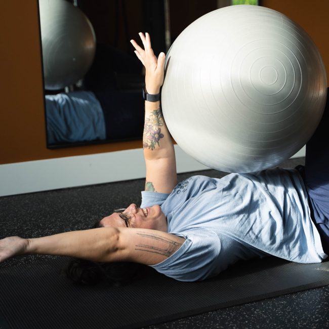 Female client performing a dead bug exercise during a personal training session in her Portland apartment gym