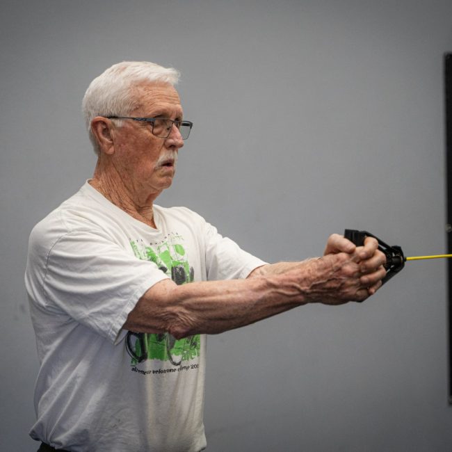 Older man performing a Pallof press hold to strengthen his core and resist trunk rotation.